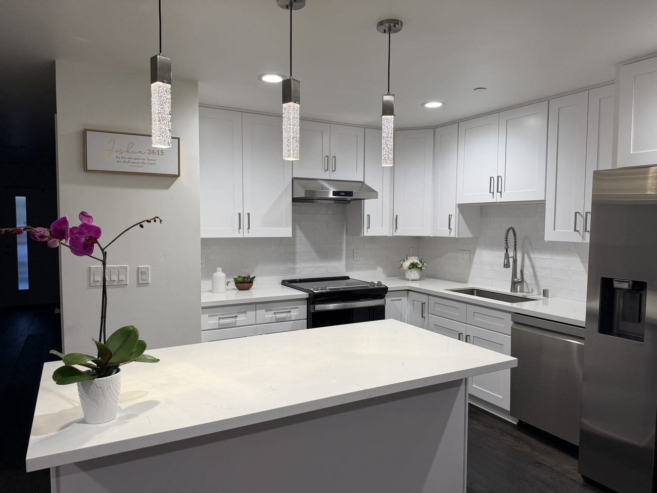 Finished white shaker kitchen with a quartz island and pendant lighting