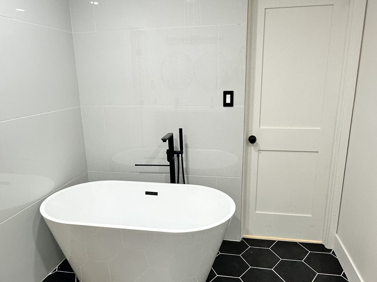 Bathroom remodel with a freestanding tub and black hex tile floor